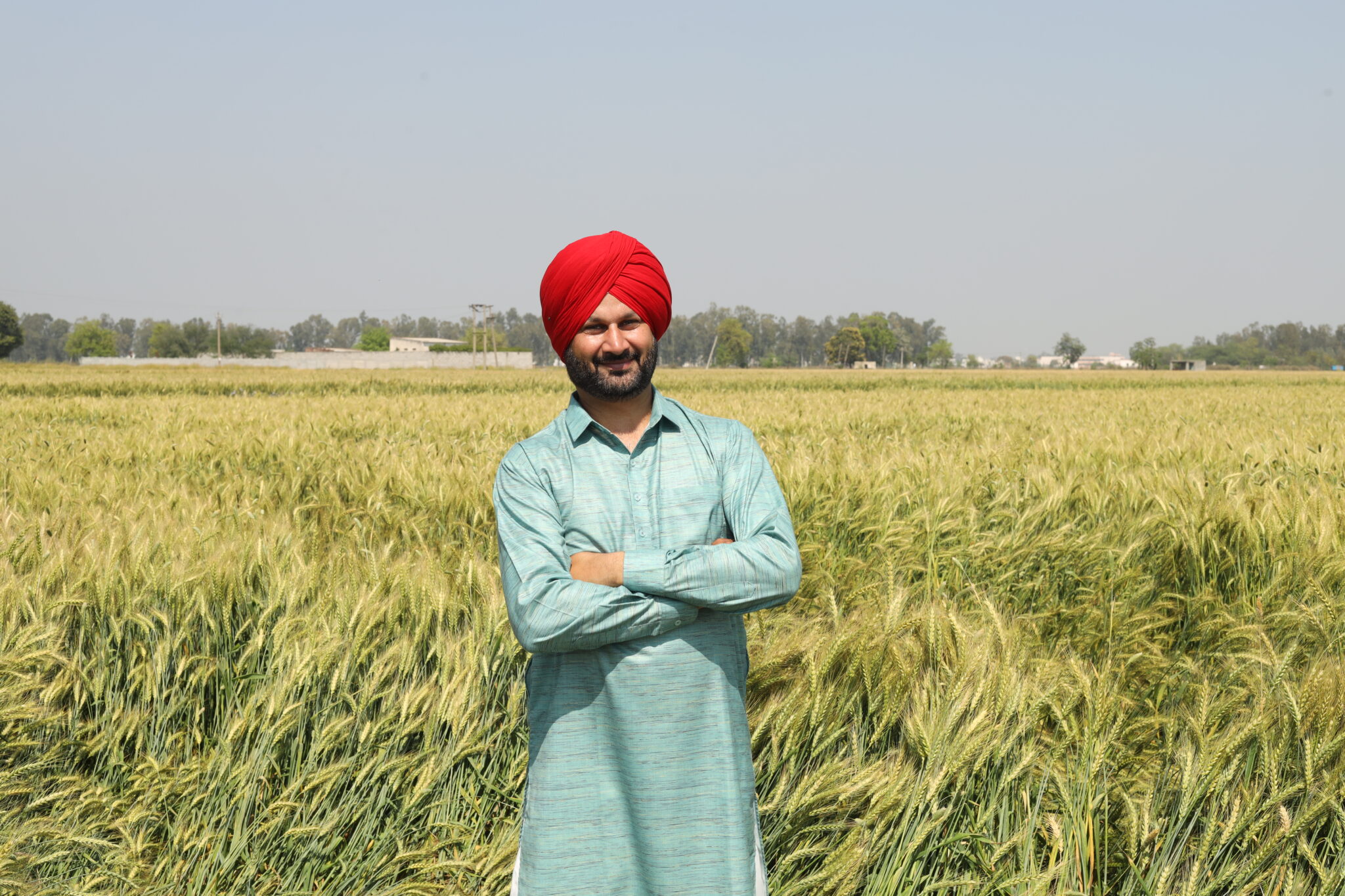 Man standing in a wheat field, smiling.